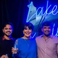 President Mantella smiles and cheers with a group of grads in front of Laker sign